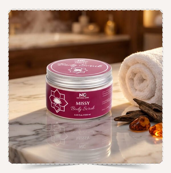 عبوة مقشر الجسم ميسي Missy Body Scrub نبيذية على سطح رخامي مع قطع عود وأحجار عنبر.