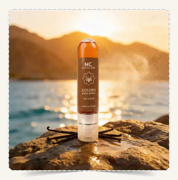 معطر الجسم الذهبي Golden Body Spray على صخرة أمام البحر وقت الغروب مع رذاذ معطر وأعواد الفانيليا.