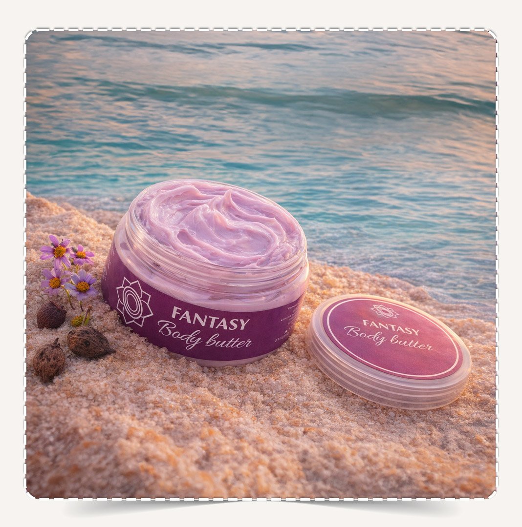 زبدة الجسم فانتسي Body Butter Fantasy مفتوحة تظهر القوام البنفسجي الفاتح الكثيف على الشاطئ.