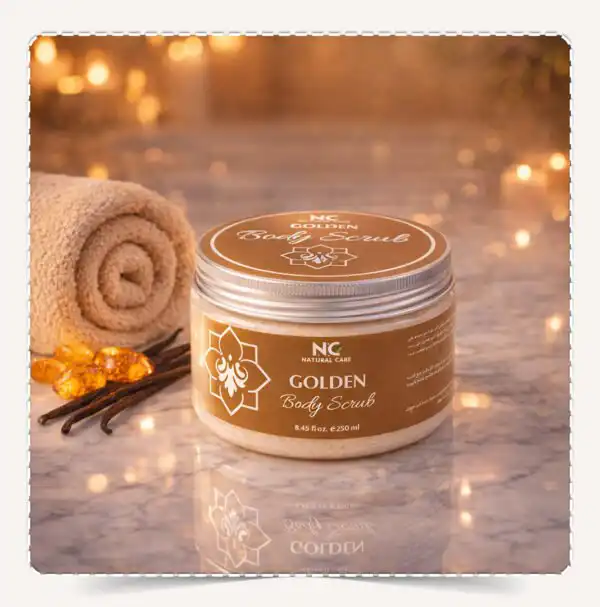 عبوة مقشر الجسم جولدن Golden Body Scrub بنية على سطح رخامي مع منشفة وأعواد فانيليا وأحجار عنبر.