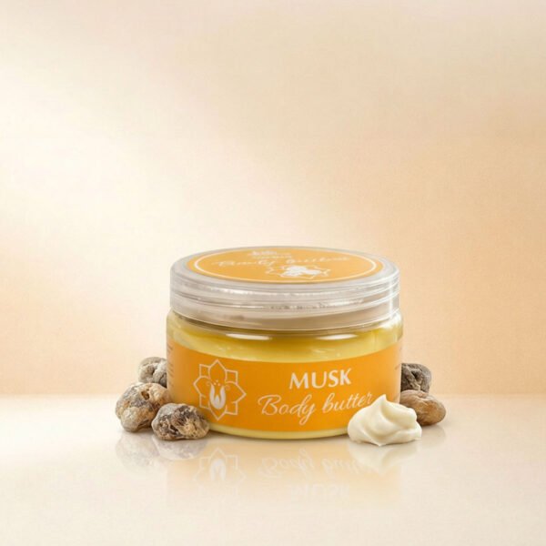 صورة إعلانية تعرض أفضل زبدة الجسم مسك Body Butter Musk من ناتشرال كير عمان، تبرز العبوة الدائرية الشفافة بملصقها البرتقالي الجذاب محاطة بأحجار المسك الطبيعية الخام ودوامة من زبدة الشيا البيضاء على سطح زجاجي عاكس.