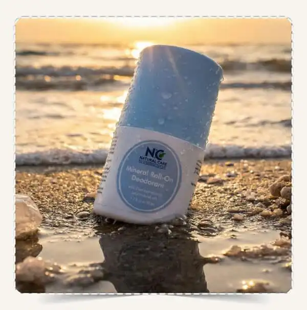 عبوة مزيل عرق رول اون معدني Mineral Roll-on Deodorant بحجم 50 مل على رمال الشاطئ وقت الغروب.