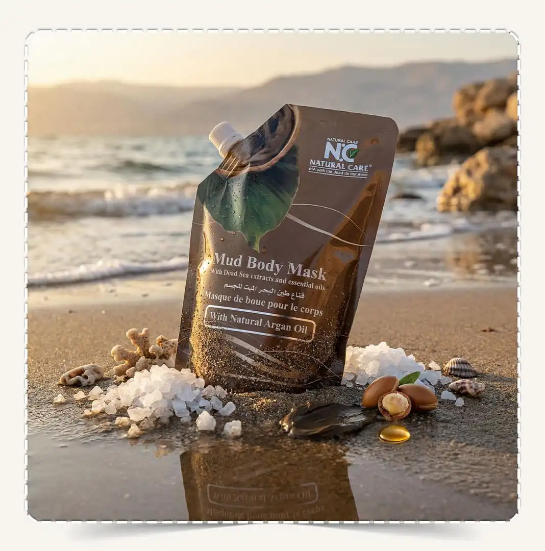 قناع طين البحر الميت للجسم Mud Body Mask على رمال الشاطئ في عمان مع انعكاس الماء.