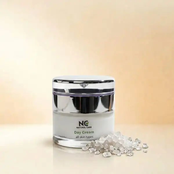 عبوة كريم النهار المرطب والمغذي Day Cream من ناتشرال كير عمان، بجانب بلورات نقية من أملاح البحر الميت التي تعكس الترطيب الطبيعي والحماية اليومية للبشرة.