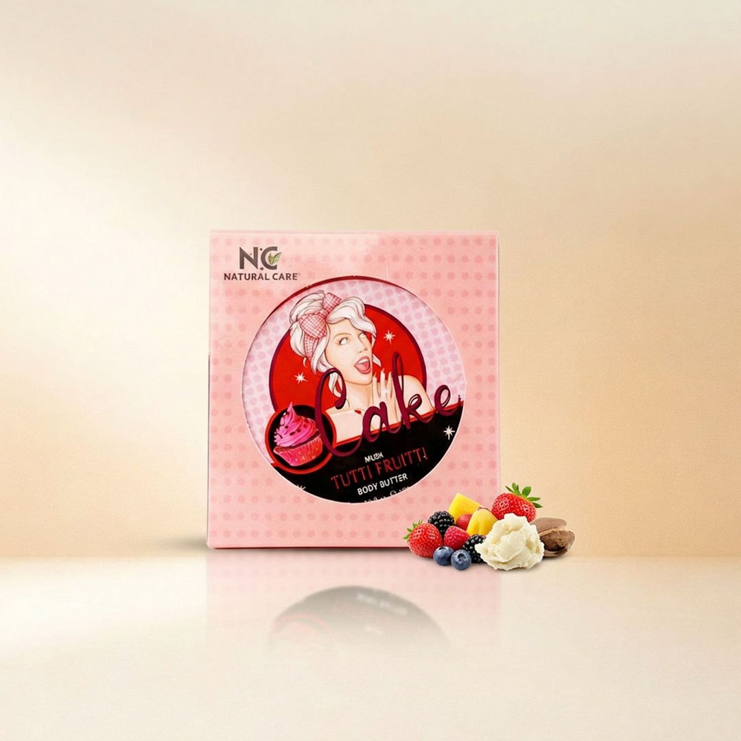 صورة إعلانية تعرض أفضل زبدة الجسم الطبيعية توتي فروتي Tutti Fruitti Natural Body Butter من ناتشرال كير عمان، يبرز صندوق التغليف الوردي المنقط برسمة كلاسيكية محاطاً بتشكيلة من الفواكه الاستوائية والتوت الطازج مع قطعة من زبدة الشيا الخام على سطح زجاجي عاكس.
