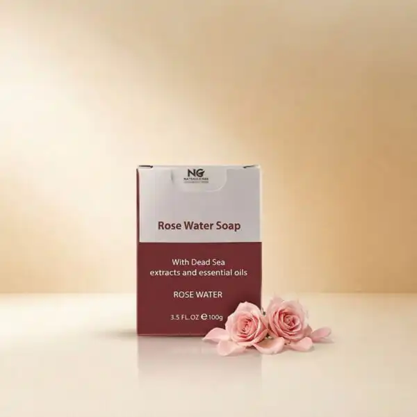 عبوة صابون ماء الورد (Rose Water Soap) من ناتشرال كير عمان، بجانب زهور الورد الطبيعية المتفتحة لتعكس النضارة والترطيب والرائحة العطرية الفاخرة.