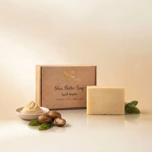 عبوة وصندوق صابونة زبدة الشيا الطبيعية - Shea Butter Soap من ناتشرال كير عمان، بجوار ثمار الشيا وزبدة الشيا الخام لتعكس الترطيب الطبيعي العميق.