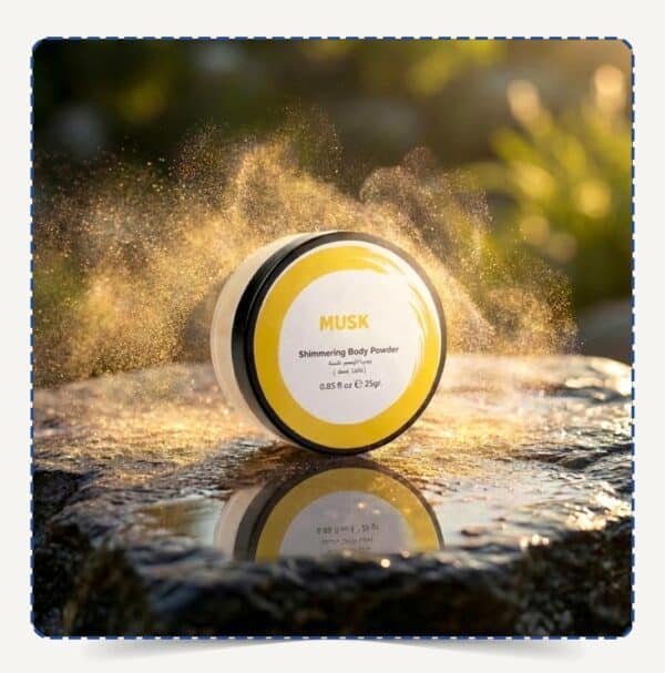 علبة Musk Body Powder دائرية بلمسات صفراء وسط تناثر ذرات البودرة اللامعة الذهبية تحت الإضاءة