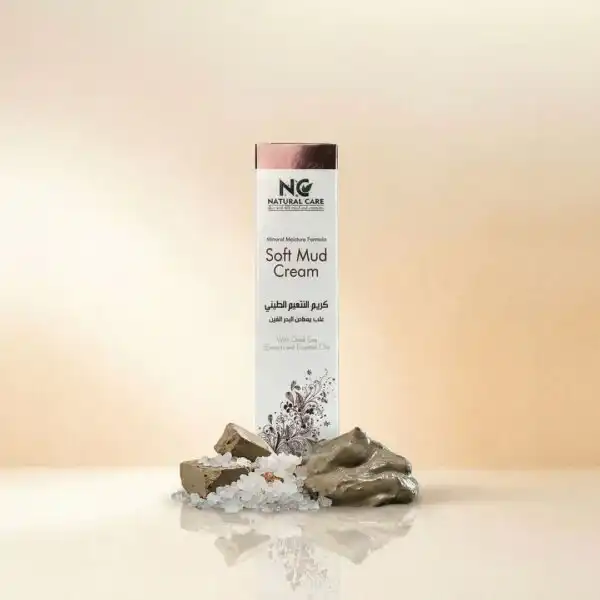 صندوق عبوة كريم التنعيم الطيني Soft Mud Cream من ناتشرال كير عمان، يعرض باحترافية بجانب قطع من الطين الطبيعي وأملاح البحر الميت ومسحة توضح قوام الكريم الغني.