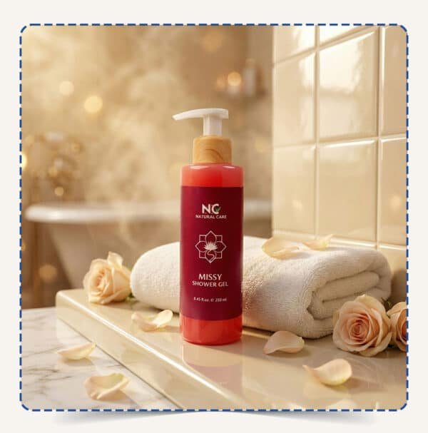 Missy Shower Gel | شاور جيل ميسي من Natural Care Oman زجاجة بمضخة بيضاء وسائل وردي مع منشفة وورود في حمام بإضاءة دافئة