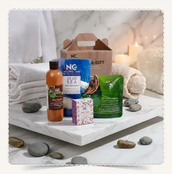 بوكس البحر الميت Dead Sea Gift Box يحتوي على شامبو الطين، أملاح البحر، قناع الطين، وصابونة على سطح رخامي.