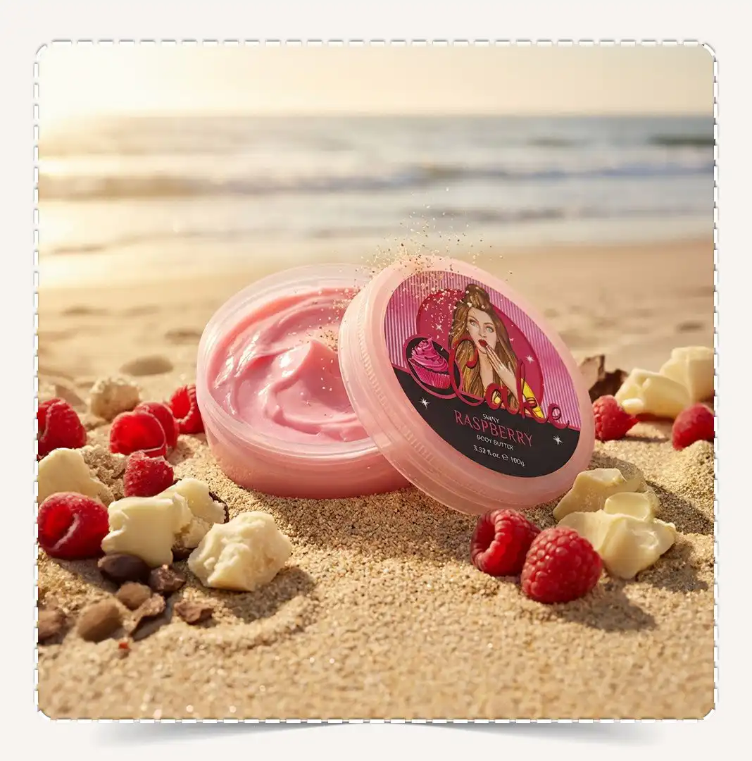 أفضل زبدة جسم طبيعية برائحة الراسبيري Raspberry Natural مفتوحة تظهر القوام الوردي الكريمي مدفونة في رمال الشاطئ مع زبدة الشيا.