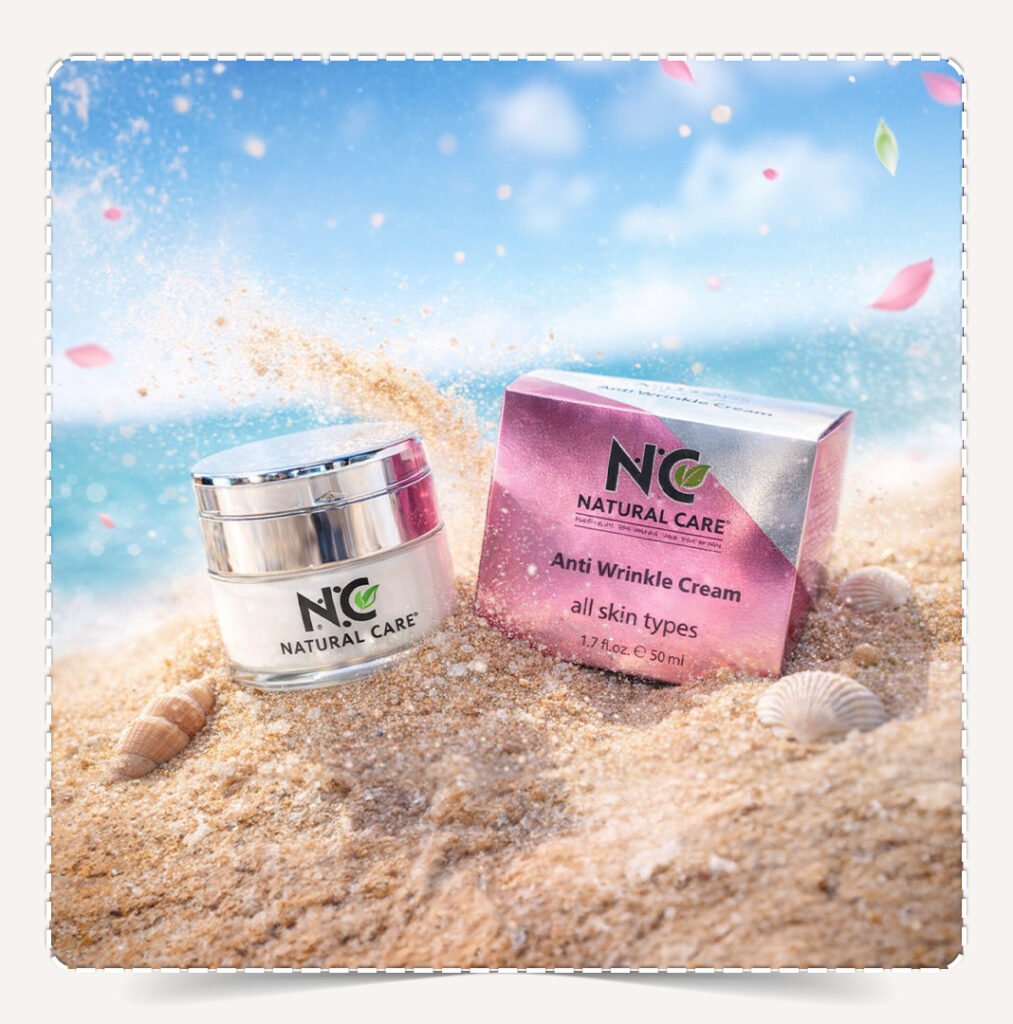 كريم Anti-Wrinkle مدفون في رمال الشاطئ مع أصداف وبتلات وردية متطايرة.