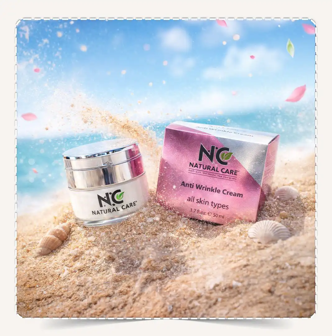 كريم Anti-Wrinkle مدفون في رمال الشاطئ مع أصداف وبتلات وردية متطايرة.