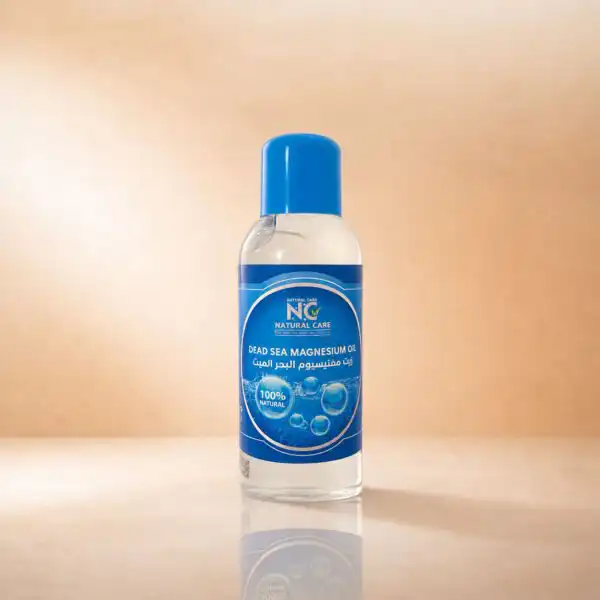 زجاجة زيت المغنيسيوم Magnesium Oil من Natural Care على سطح رخامي مع منشفة وبلورات ملح البحر الميت وتأثير تموجات الماء.