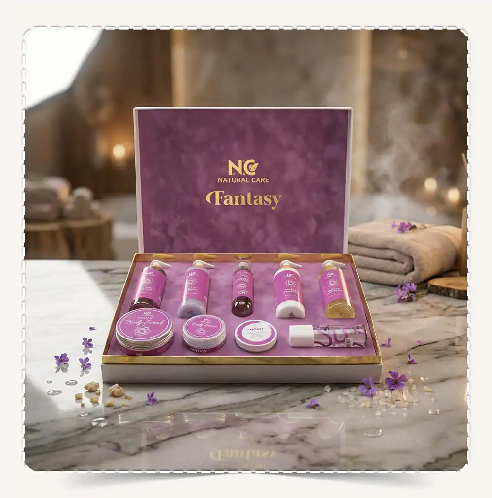 أفضل صندوق مجموعة فانتزي | Fantasy Collection للعناية بالجسم معروض على رخام أبيض في أجواء سبا فاخرة مع زهور برية بنفسجية.