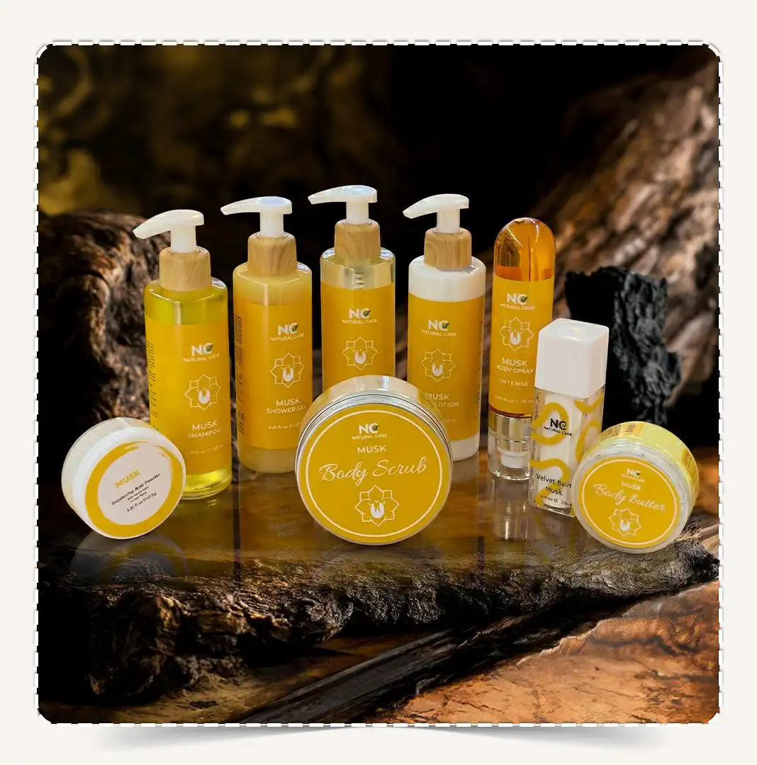 أفضل صندوق مجموعة مسك | MUSK Collection للعناية بالجسم بعبوات صفراء معروض على رخام أبيض في أجواء سبا فاخرة مع أحجار العنبر والمسك.