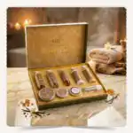 صندوق مجموعة جولدن | Golden Collection المفتوح بعبواته الفاخرة على رخام أبيض في أجواء سبا دافئة مع أعواد الفانيليا وأملاح البحر.