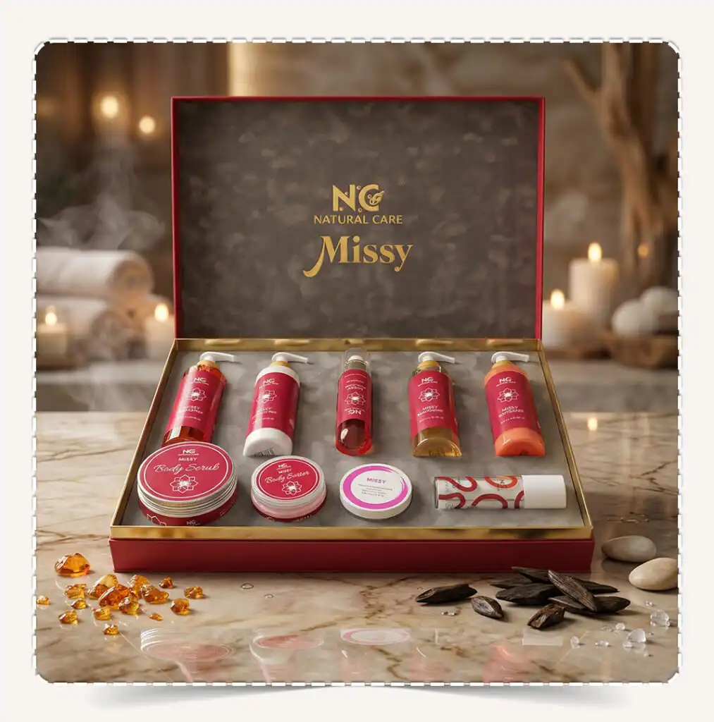 صندوق مجموعة ميسي | Missy Collection المفتوح بعبواته الحمراء الفاخرة على رخام أبيض في أجواء سبا دافئة مع أحجار العنبر وأخشاب العود.