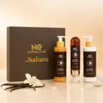عبوة ومنتجات مجموعة العناية اليومية صحارى من ناتشرال كير عمان، صندوق فاخر يحتوي على ثلاثة منتجات: لوشن للجسم، معطر جسم مركز، وجل استحمام، محاطة بزهرة الفانيليا وأحجار المسك الأبيض.